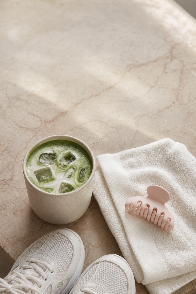Iced matcha and a gym towel on a marble table after class